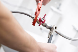 Hands of a plumber fixing a valve for backflow prevention. 