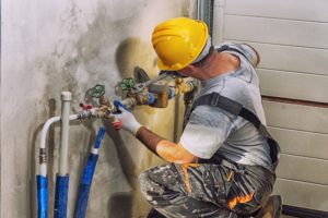 plumber works on backflow repair on a pipe