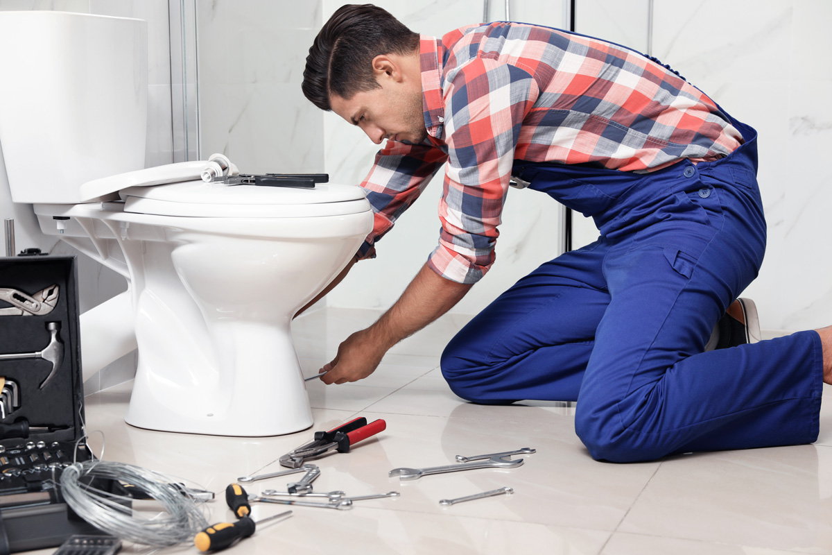 A man using tools to repair a toilet in El Paso.